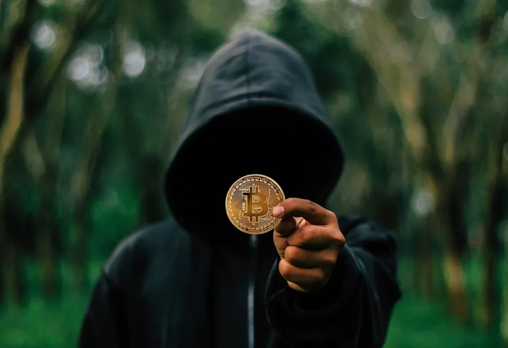 A MAN IN HOODIE HOLDING BITCOIN IN HAND